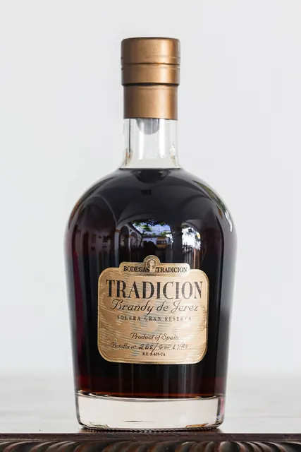 Brandy Tradición se sklenkou a starými knihami.