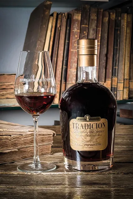 Brandy Tradición ve sklenici a lahvi.
