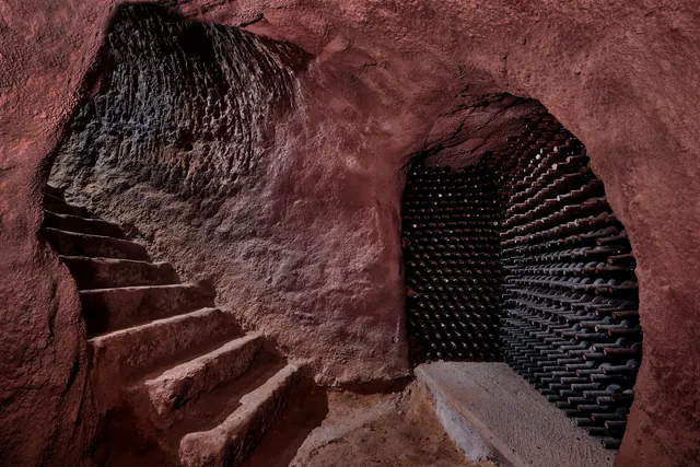 Kamenné schody a láhve v historickém sklepě Cillar de Silos.